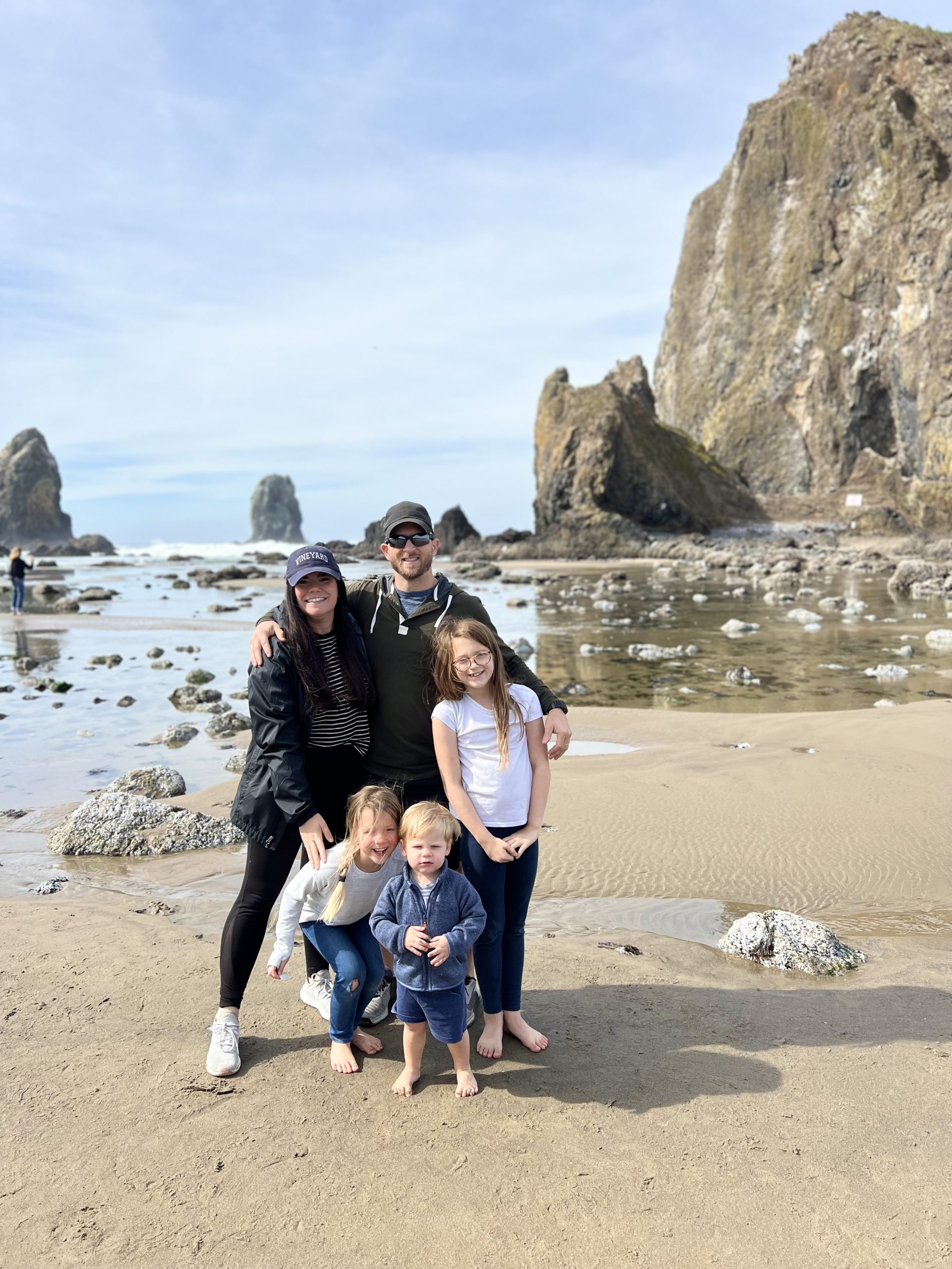 family in front of haystack rock in oregon