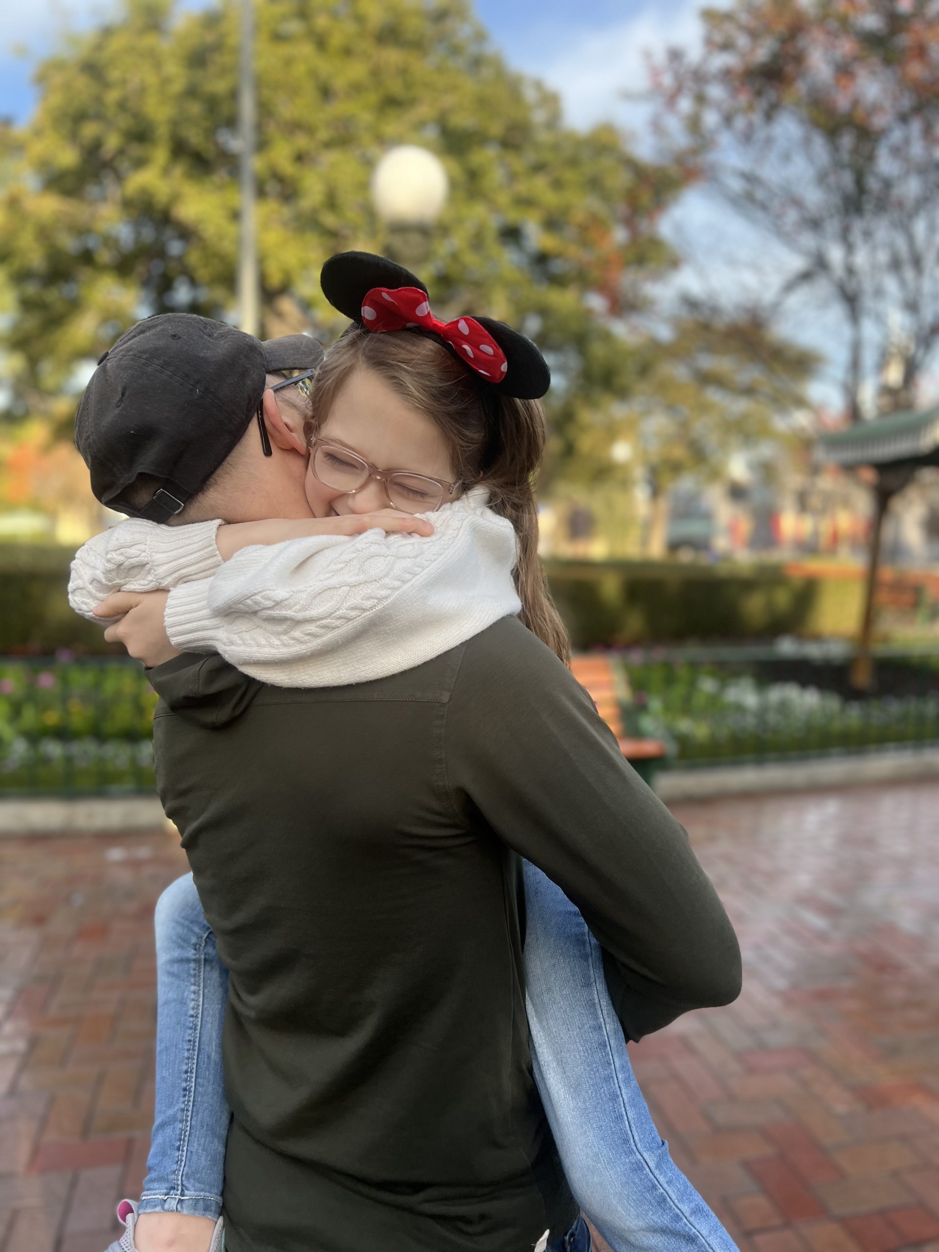 girl hugging her dad with mickey ears on at disneyland