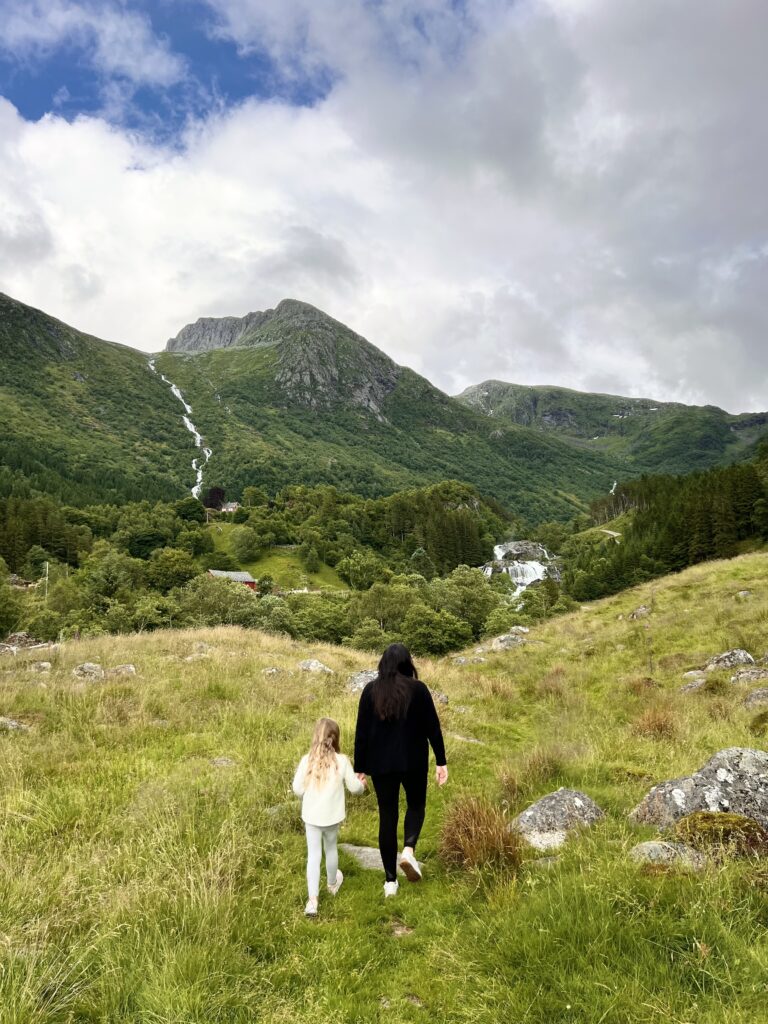Mom and daughter hiking a green mountain valley with waterfalls on a family trip funded with points