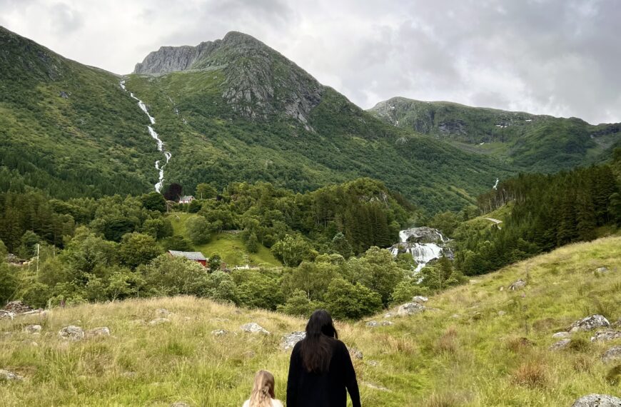 Mom and daughter hiking a green mountain valley with waterfalls on a family trip funded with points